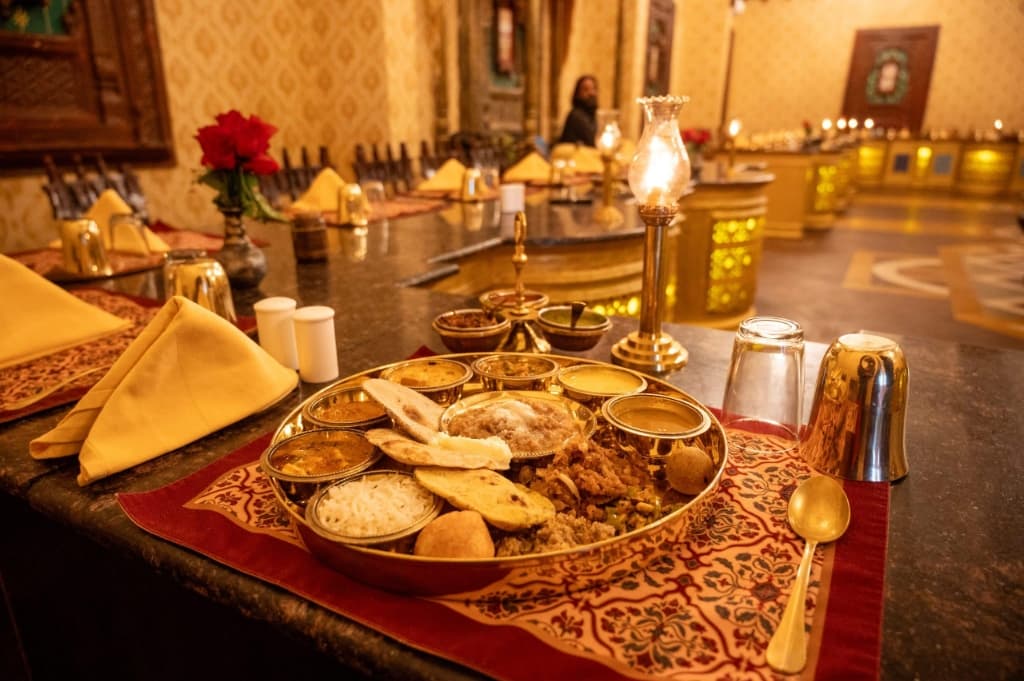 Candlelit royal dining hall thali arrangement with brass goblets and golden tableware