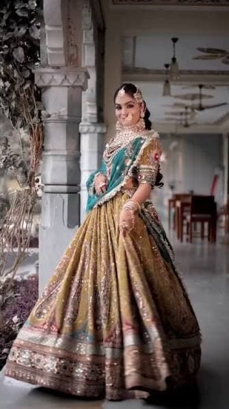 Royal bridal portrait in gold and teal embroidered lehenga in palatial corridor at Castle Narela