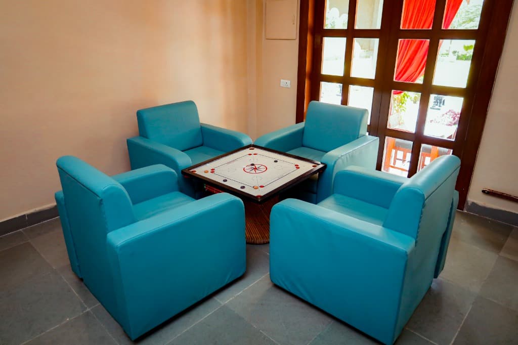 Carrom board setup with 4 comfortable blue leather armchairs